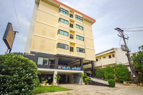 a tall yellow building with a sign in front of it at AJ Residence in Phuket Town
