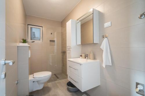Apartment Ana في مارينا: حمام ابيض مع مرحاض ومغسلة