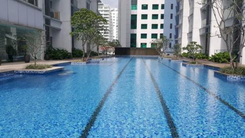 M Suites Jalan Ampang by Plush في كوالالمبور: مسبح ازرق كبير مع مباني في الخلف