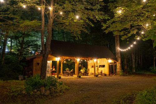 a cabin in the woods at night with lights at Kizuna Lodge & BBQ Centre in Hakuba