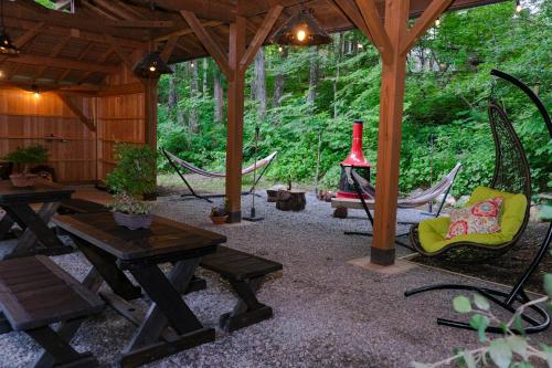 a patio with picnic tables and hammocks in a forest at Kizuna Lodge & BBQ Centre in Hakuba