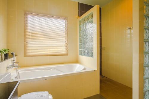 a yellow bathroom with a tub and a window at AJ Residence in Phuket Town