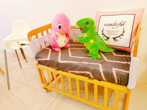 two stuffed dinosaurs are sitting on a crib at Legoland-Happy Wonder Suite,Elysia-8pax,100MBS in Nusajaya