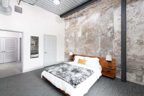 um quarto com uma cama e uma parede de pedra em Flexhome Brewery District 1BR Apt M10 - READ INFO em Milwaukee