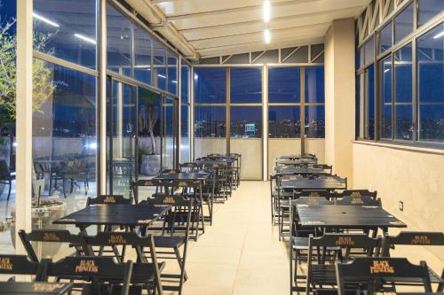a row of tables and chairs in a room with windows at Lagoon Prime Hotel in Lagoa Santa
