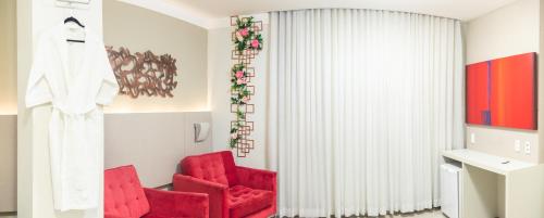 a living room with red chairs and a curtain at Lagoon Prime Hotel in Lagoa Santa