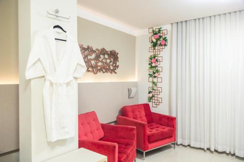 a room with two red chairs and a robe on a rack at Lagoon Prime Hotel in Lagoa Santa