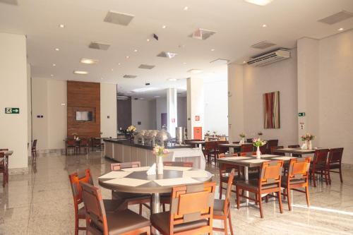 a restaurant with tables and chairs and a kitchen at Lagoon Prime Hotel in Lagoa Santa