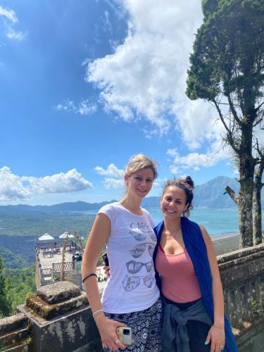 two women standing on top of a wall with a camera at Triangle House and hot spring in Kintamani