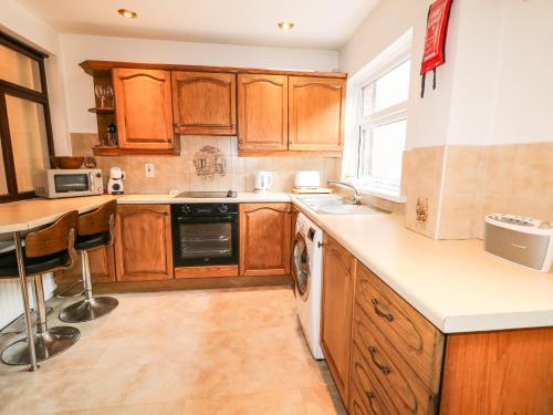 a kitchen with wooden cabinets and a sink and a dishwasher at Number 91 in Belfast