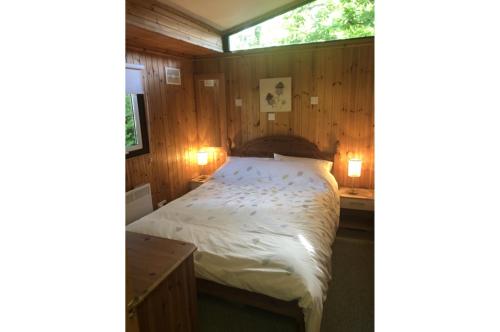 a bedroom with a bed in a wooden wall at Nuthatch Lodge is set in 24 acres of wood, parkland near the village of Cenarth in Newcastle Emlyn