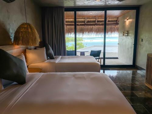 a hotel room with two beds and a view of the ocean at Hotel Amainah Bacalar Adults Only in Bacalar