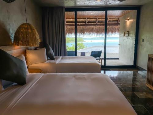 Habitación de hotel con 2 camas y vistas al océano en Hotel Amainah Bacalar Adults Only, en Bacalar