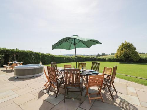 a patio with a table and chairs and an umbrella at Lea Farm House in Kidderminster
