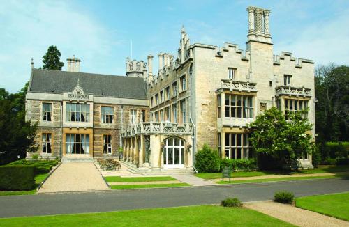 a large stone building with a tree in front of it at Orton Hall Hotel & Spa in Peterborough