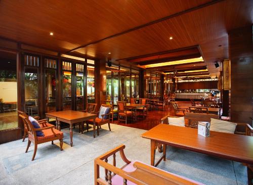 a restaurant with wooden tables and chairs and windows at Siripanna Villa Resort & Spa Chiang Mai -SHA Extra Plus in Chiang Mai