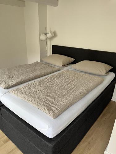 uma cama grande com uma moldura preta e lençóis brancos em Citi Wohnung em Husum