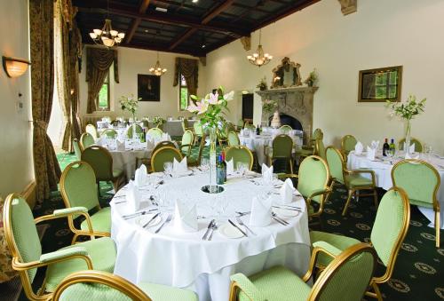 a banquet room with white tables and chairs and a fireplace at Orton Hall Hotel & Spa in Peterborough