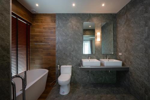 a bathroom with two sinks and a tub and a toilet at Orchid Paradise Homes OPV429 in Hua Hin