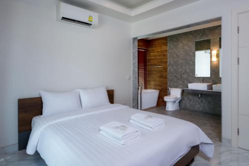 a bedroom with a white bed and a bathroom at Orchid Paradise Homes OPV429 in Hua Hin