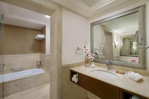 a bathroom with a sink and a tub and a mirror at Vivanta Katra Vaishno Devi in Katra