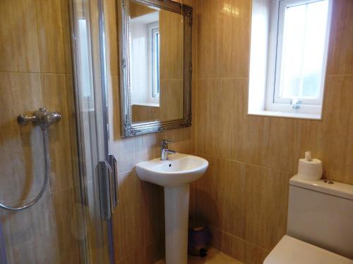 a bathroom with a sink and a shower with a mirror at Bailey Ground Lodge in Seascale