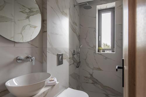 a bathroom with a white sink and a mirror at Mystic Garden Villas in Zakynthos Town