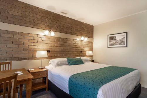 a hotel room with a bed and a desk and a bed sidx sidx sidx sidx at Stagecoach Motel Wodonga in Wodonga
