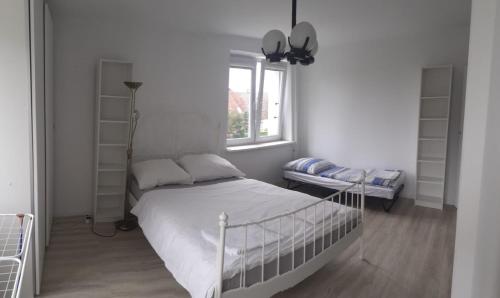 um quarto branco com uma cama e uma janela em Mieszkanie Wakacyjne Smołdzino em Smoldzino