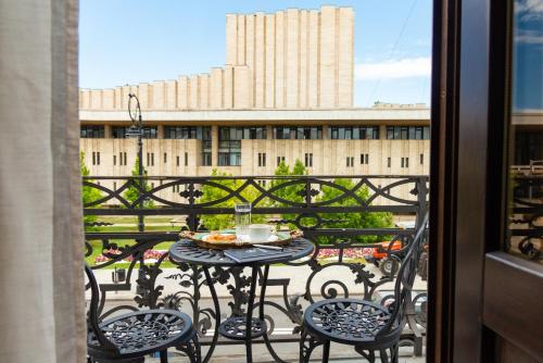 a table and chairs on a balcony with a view of a building at Hotel Splendid 1900 in Craiova