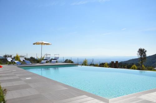 a large swimming pool with chairs and an umbrella at Podere Ortaglia di Sopra in Castiglion Fiorentino