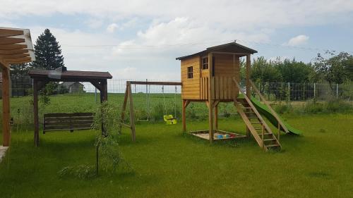 a playground with a tree house and a slide at Domki nad Nieliszem - dom brzozowy in Nielisz