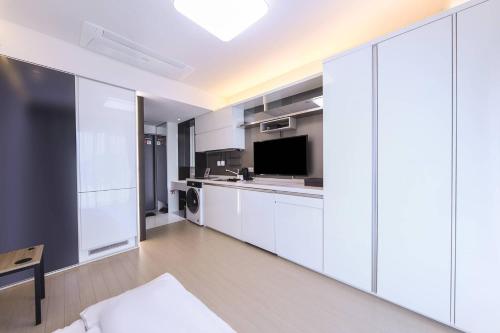 a large kitchen with white cabinets and a tv at Skytop Hotel Incheon Airport in Incheon