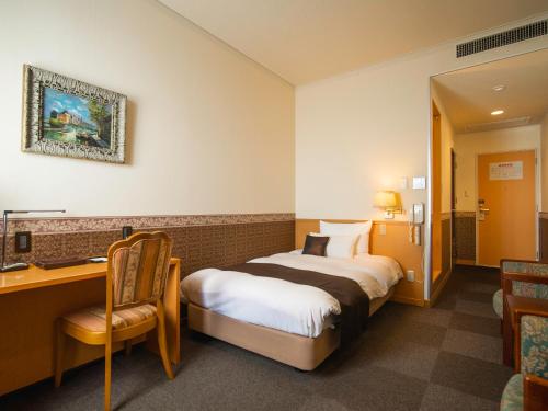 高知市にあるCHRESセリーズのベッド、デスク、椅子が備わるホテルルームです。