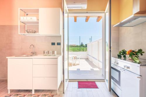 a kitchen with white cabinets and a large window at Casa Vacanza Brucoli Mare 1 in Brucoli