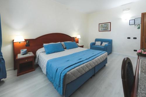 a bedroom with a large bed and two blue chairs at Edra Palace Hotel & Ristorante in Cassino