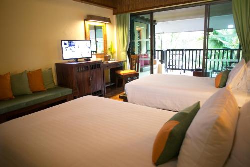 a hotel room with two beds and a television at Centara Koh Chang Tropicana Resort in Ko Chang