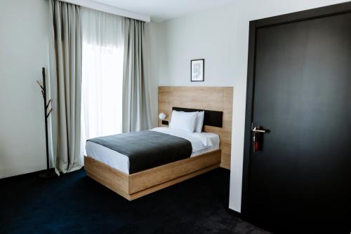 a bedroom with a bed and a large window at Hotel Septembar in Podgorica