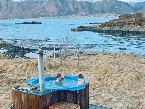two people in a hot tub next to the water at 8 person holiday home in Bølandet-By Traum in Røyra