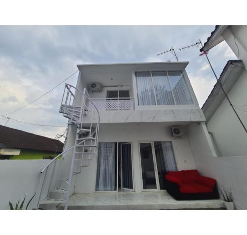 a white house with a white staircase in front of it at RedDoorz Syariah near Taruna Nusantara Magelang in Banyurojo