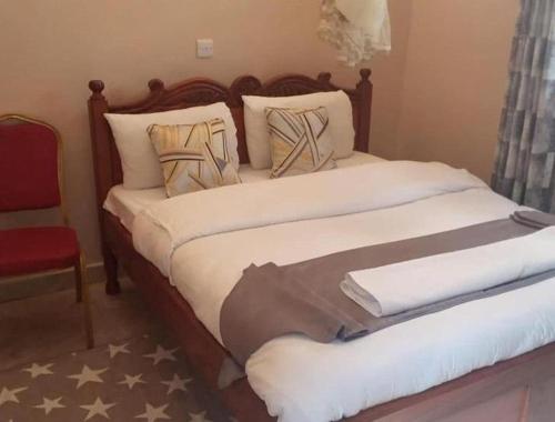 a bedroom with a large bed with a red chair at Stay.Plus Villa Serene Kitale in Kitale