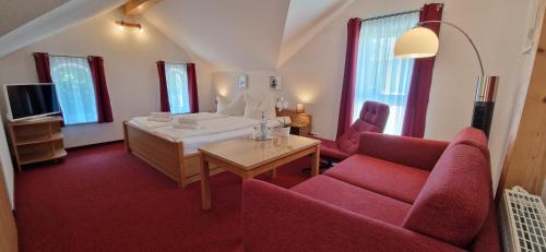 a living room with a red couch and a table at Pension Haus Waldesblick in Graal-Müritz