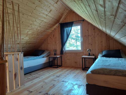een slaapkamer met 2 bedden in een houten huis bij BLISKO NATURY - domki wypoczynkowe w Dolinie Baryczy in Milicz