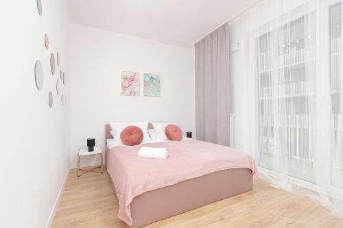 a white bedroom with a pink bed and a window at Stacja Wola Apartment Gumińska by Renters in Warsaw