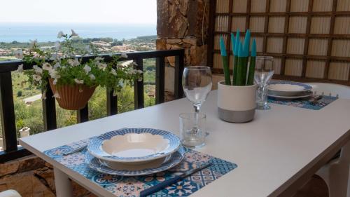 a table with plates and wine glasses on a balcony at Casa della Luna in Budoni