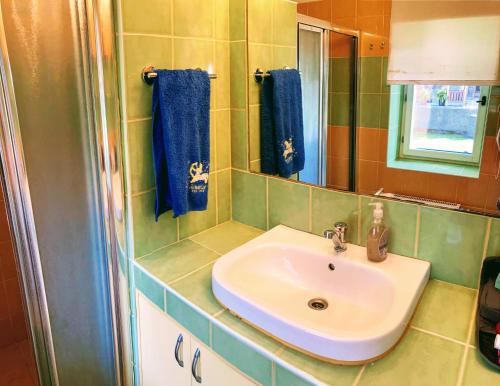 a bathroom with a sink and a mirror and blue towels at Apartmány u řeky Nežárky in Lasenitz