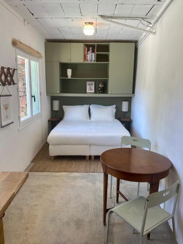 - une chambre avec un lit, une table et une chaise dans l'établissement Gîte Le Palmier - Perfectly located cosy studio with private garden, à Puissalicon
