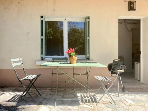 stół z dwoma krzesłami i okno z doniczką z kwiatami w obiekcie Gîte Le Palmier - Perfectly located cosy studio with private garden w mieście Puissalicon