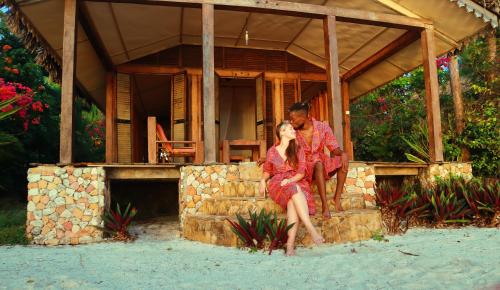 a man and a woman sitting in front of a house at Seasons Lodge Zanzibar in Pongwe