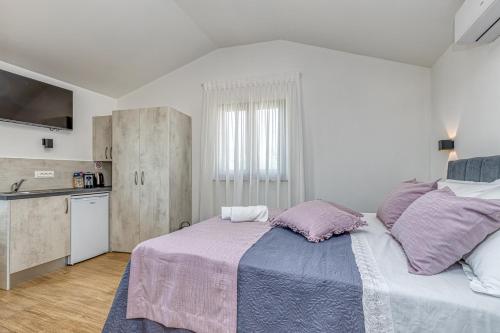 - une chambre avec un grand lit et des oreillers violets dans l'établissement Rooms Nilda, à Poreč